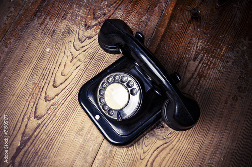 Obraz na płótnie Old black phone with dust and scratches on wooden floor w salonie