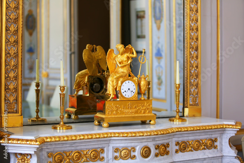 Antique clock with figurine of angel in vintage interior.