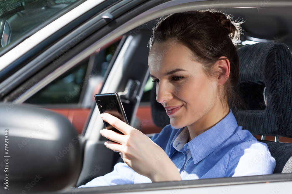 Woman texting on mobile phone at car
