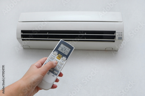 Hand with remote control directed on the conditioner on the wall