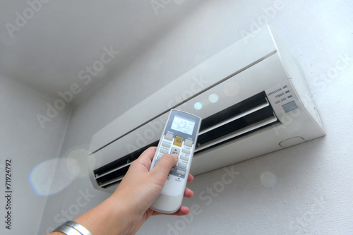 Hand with remote control directed on the conditioner on the wall