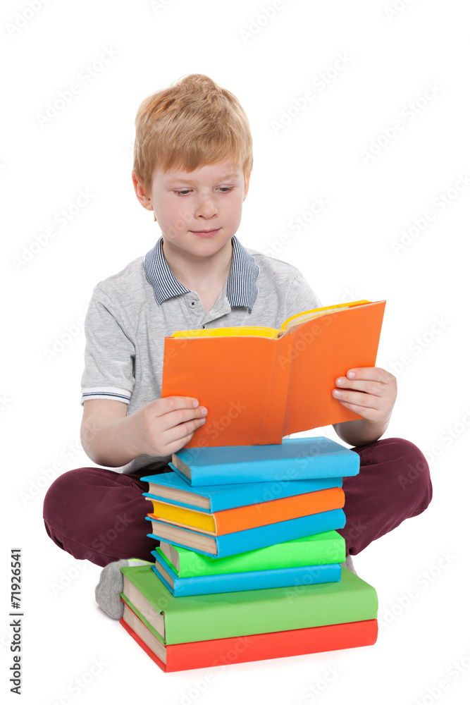 Little boy reads near the pile of books Little boy reads near the pile of books