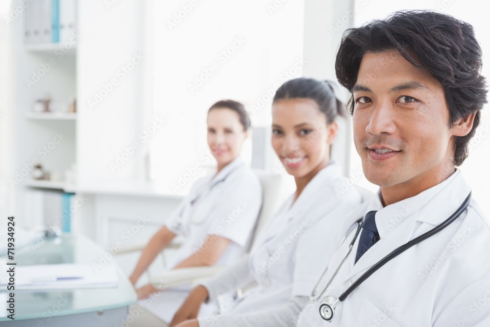 Smiling doctors sitting beside each other Smiling doctors sitting beside each other