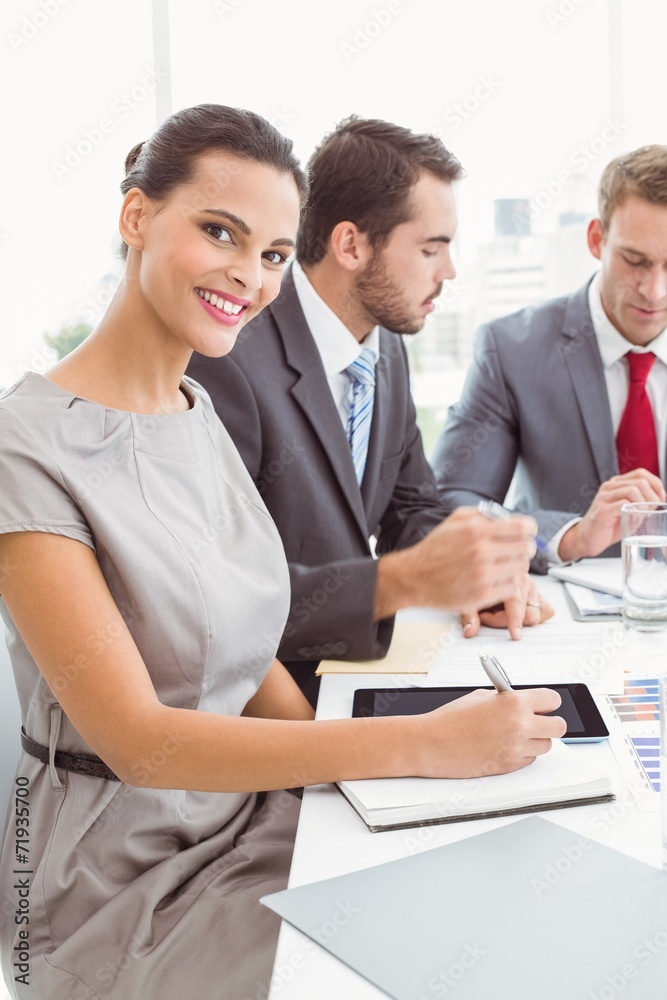 Business people writing notes in board room meeting Business people writing notes in board room meeting