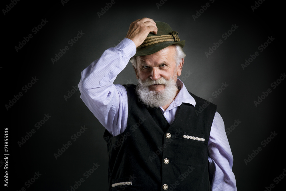 Old bavarian man in hat on black background