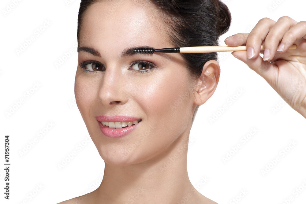 Beautiful young woman applying eyebrow brush