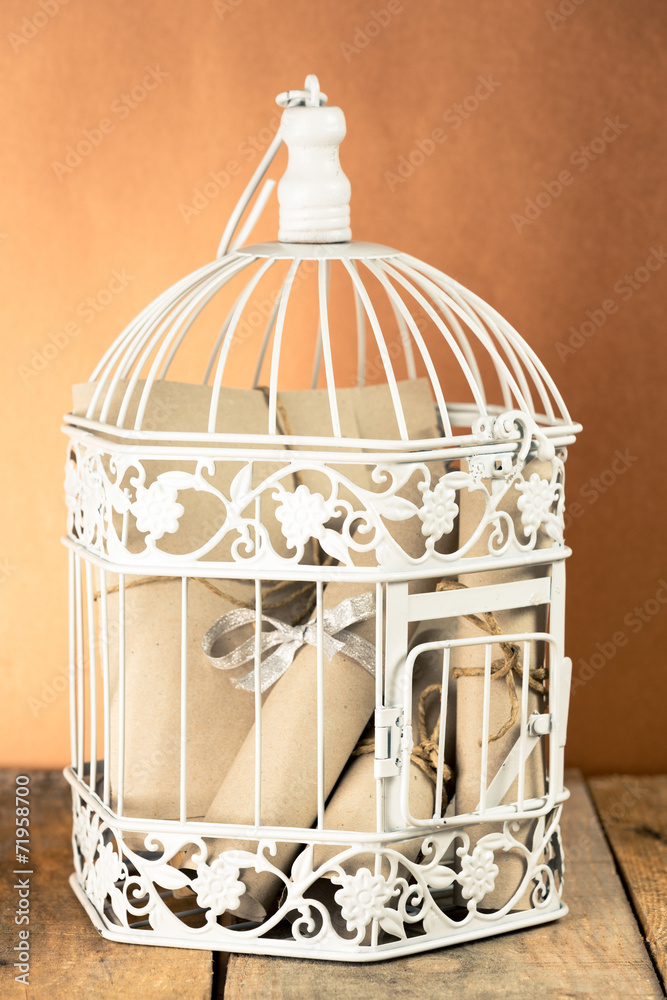 White decorative cage and bunch of rolled papers inside White decorative cage and bunch of rolled papers inside