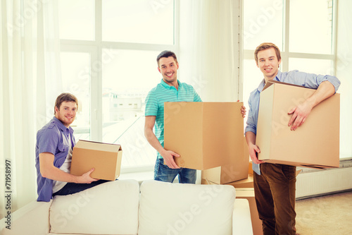 smiling male friends carrying boxes at new place © Syda Productions