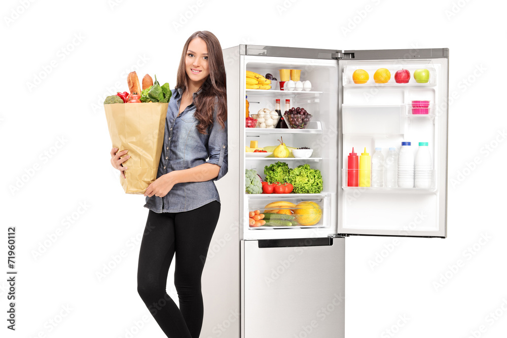 Woman holding a grocery bag by an open fridge Woman holding a grocery bag by an open fridge
