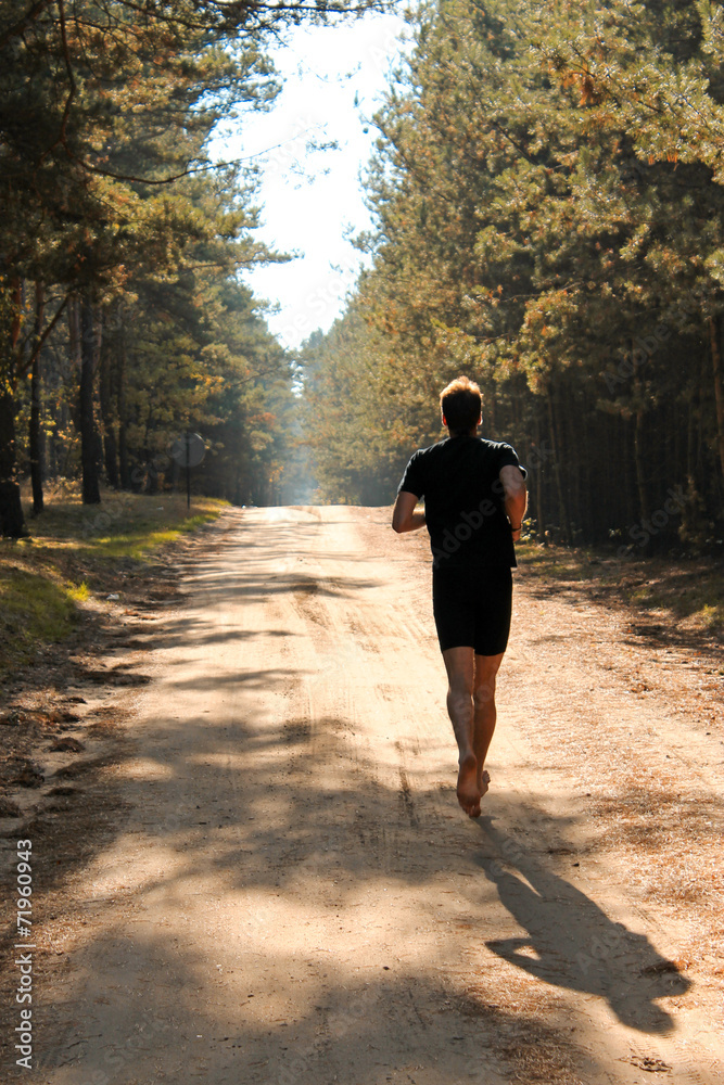 Obraz premium Barefoot runner running through autumn forest