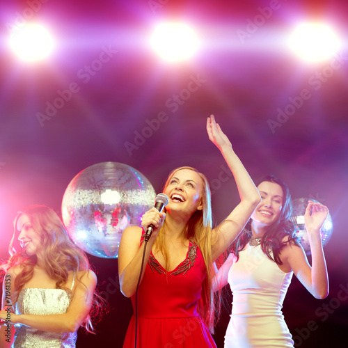 three smiling women dancing and singing karaoke