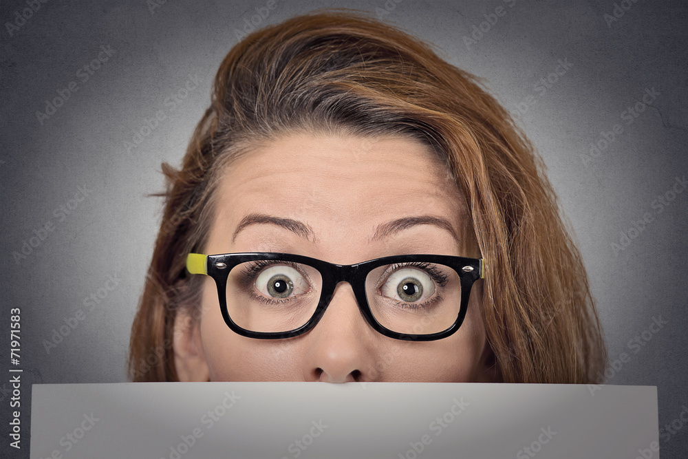 Scared surprised woman peeking over edge of blank billboard Scared surprised woman peeking over edge of blank billboard