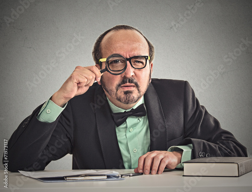 Photos businessman skeptically looking at you through magnifying glass