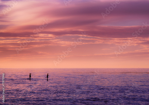 Couple paddle boarding at sunset