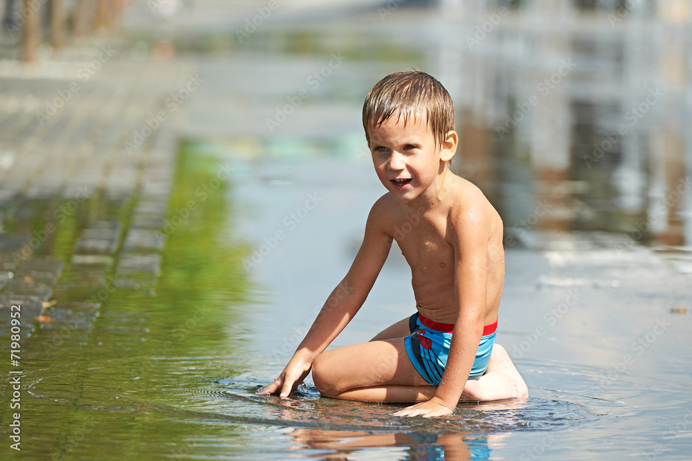 Fototapeta premium Little boy playing with water in a puddle