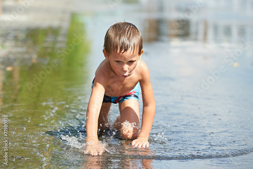 Fototapeta Naklejka Na Ścianę i Meble -  Little boy playing with water in a puddle