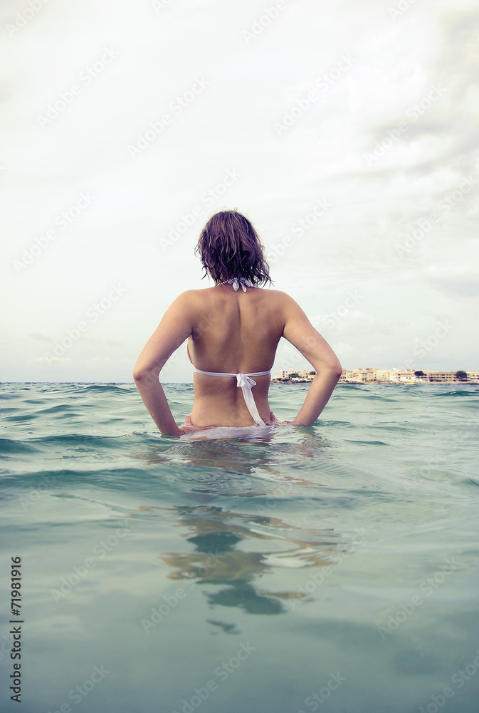 Obraz premium Young woman sunbathes in the sea. Vintage effect.