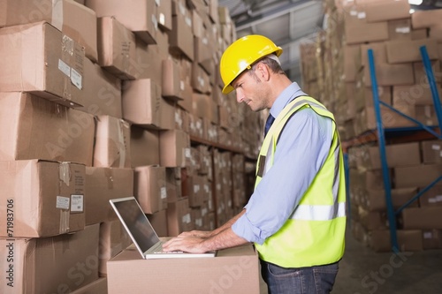 Workman using laptop at warehouse