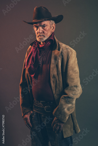Obraz na płótnie Old rough western cowboy with gray beard and brown hat. Low key w salonie