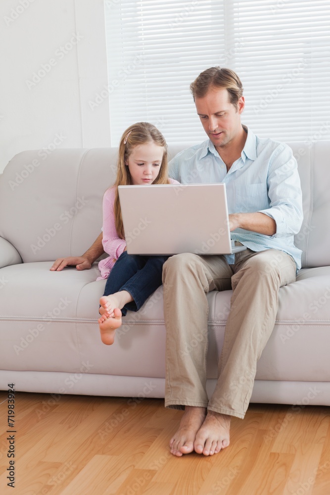 Casual father and daughter using laptop on the couch Casual father and daughter using laptop on the couch