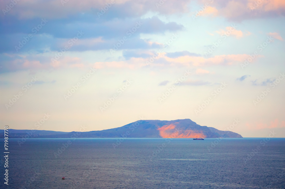 Mountain in sea at sunset