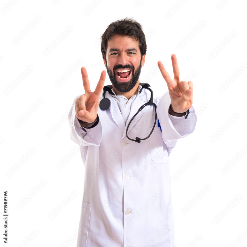 Doctor doing victory gesture over white background Doctor doing victory gesture over white background