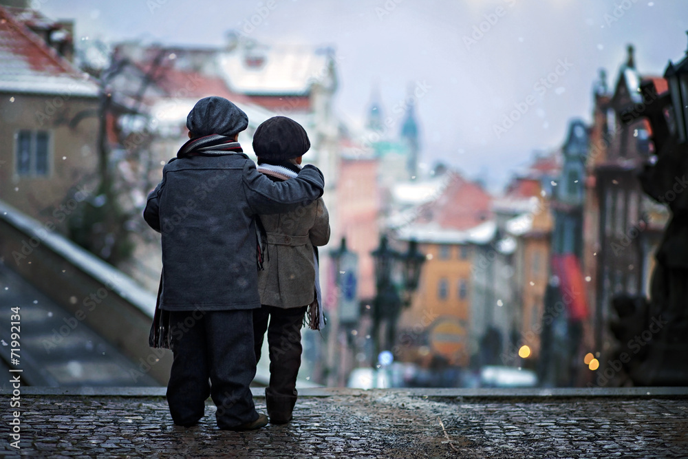 Two kids, standing on a stairs, hugging view of Prague
