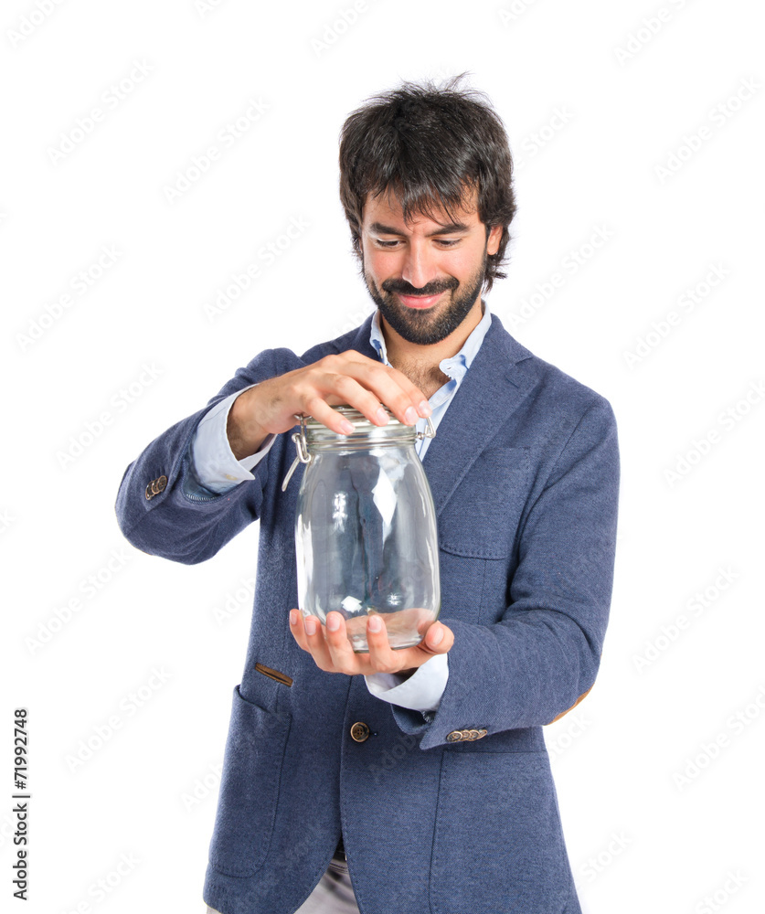 Handsome man holding an empty glass jar over isolated background Handsome man holding an empty glass jar over isolated background
