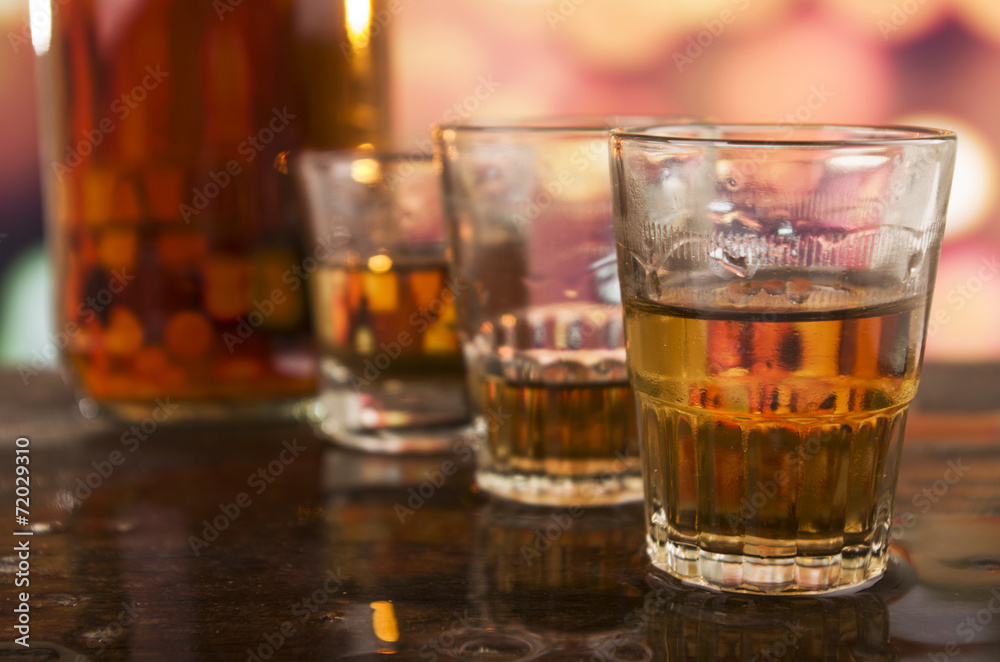 shots of rum whiskey over defocused lights background shots of rum whiskey over defocused lights background