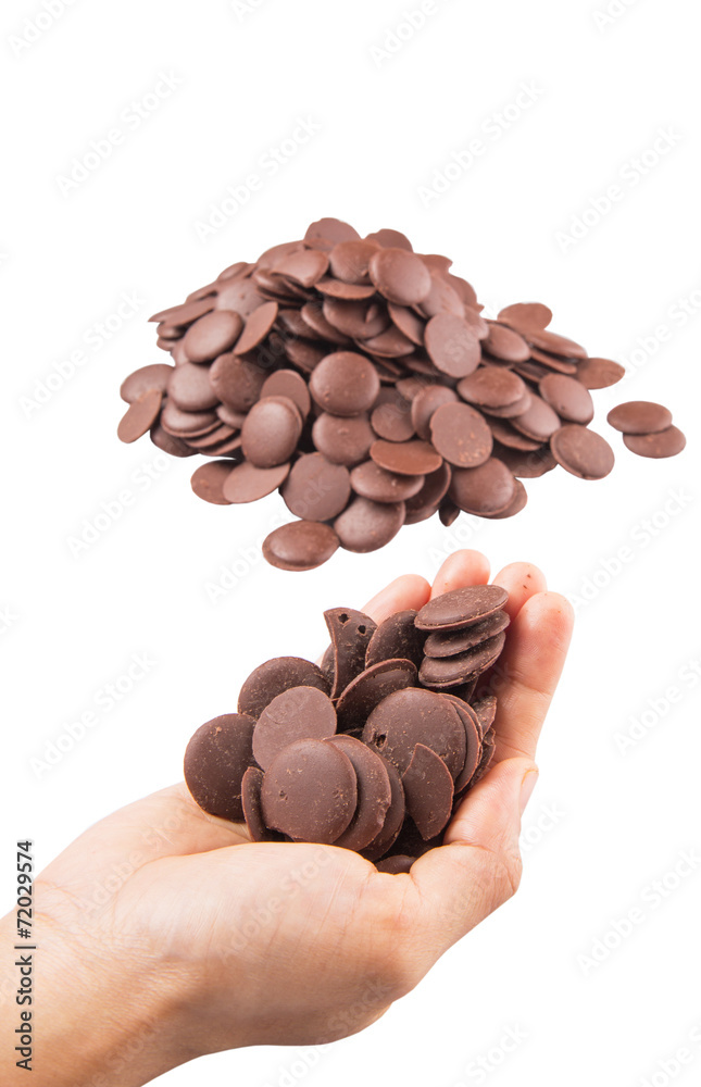 Female hand picking up chocolate button over white background Female hand picking up chocolate button over white background