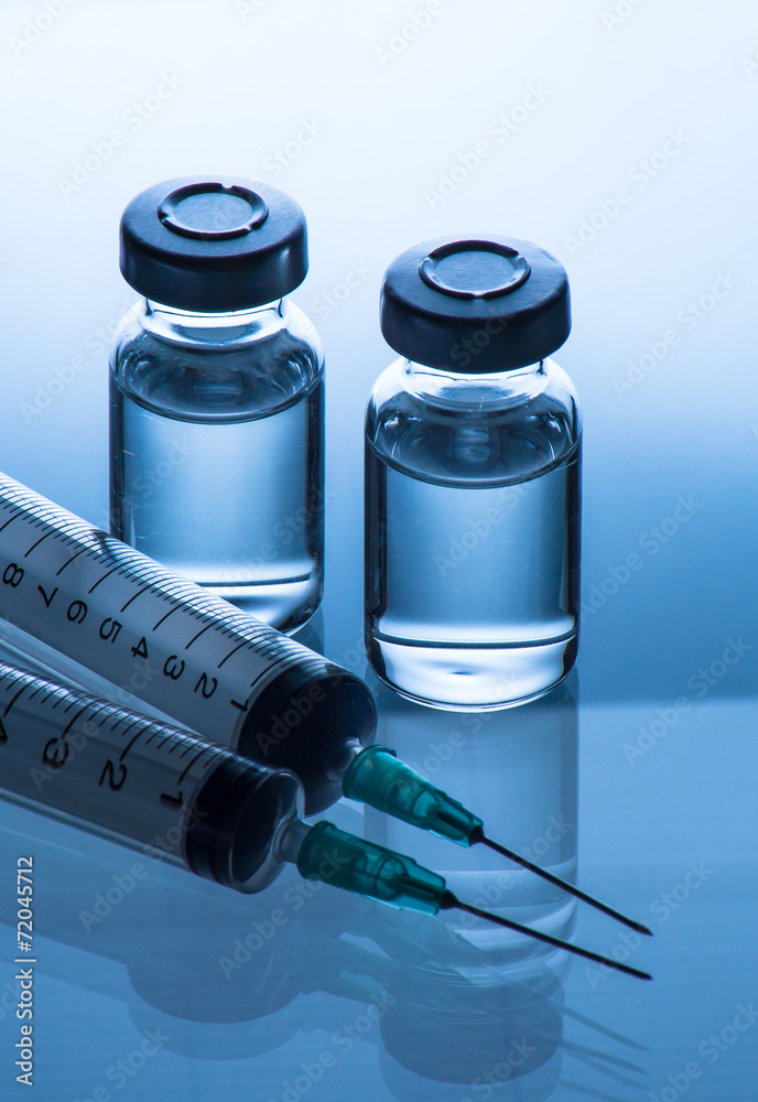 medical ampoules and syringe on blue background