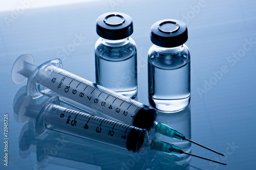 medical ampoules and syringe on blue background