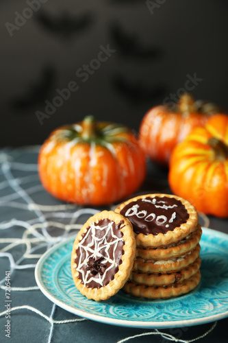 Tasty Halloween cookies on plate, on decorative spiderweb