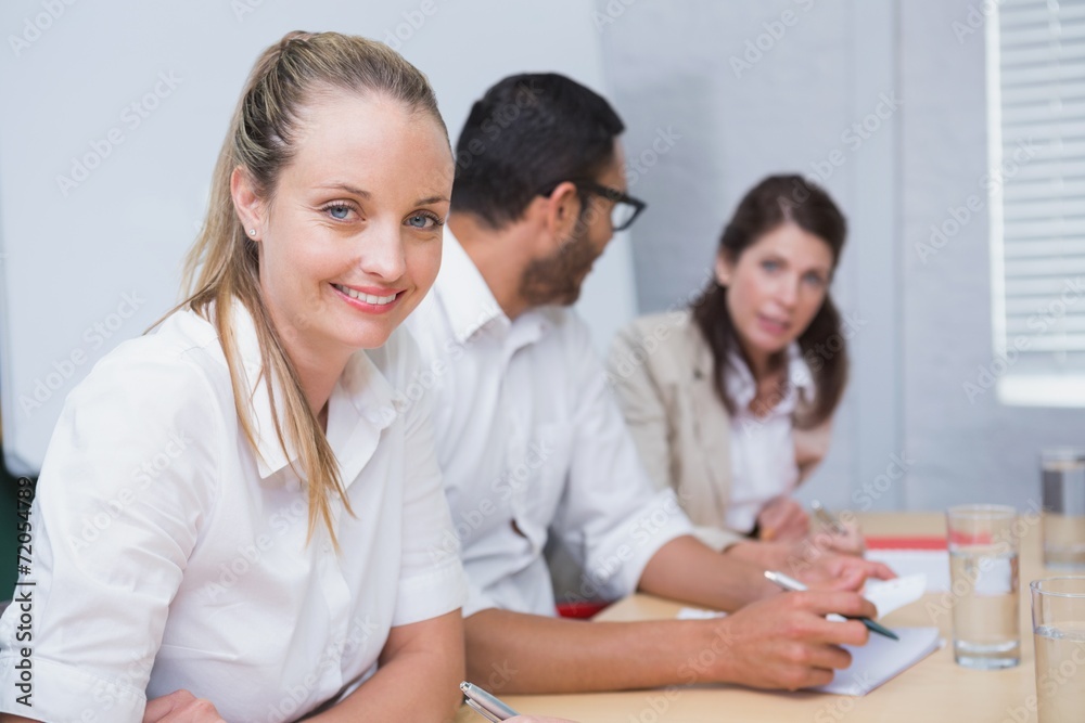 Businesswoman smiling at camera with team behind her Businesswoman smiling at camera with team behind her