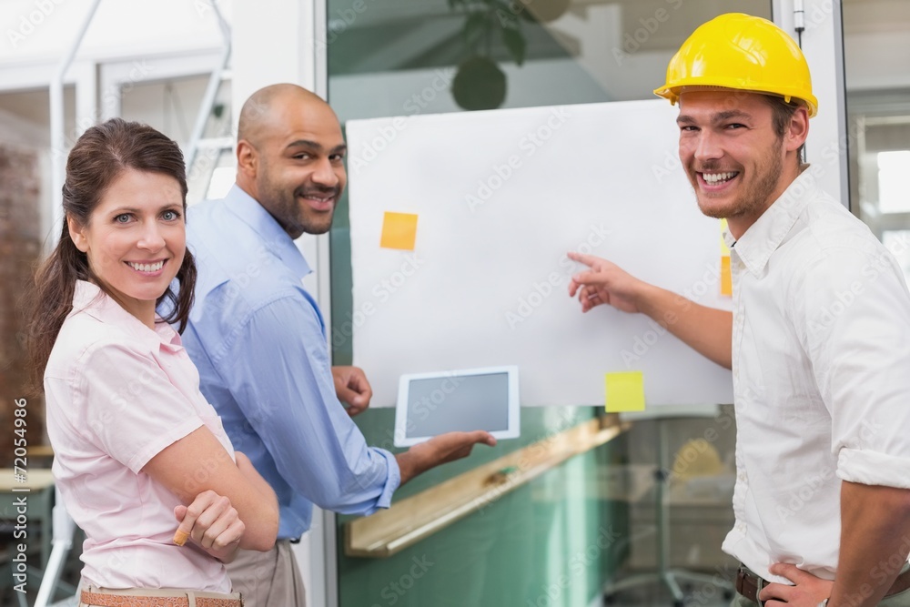 Obraz premium Smiling architect team brainstorming together using tablet