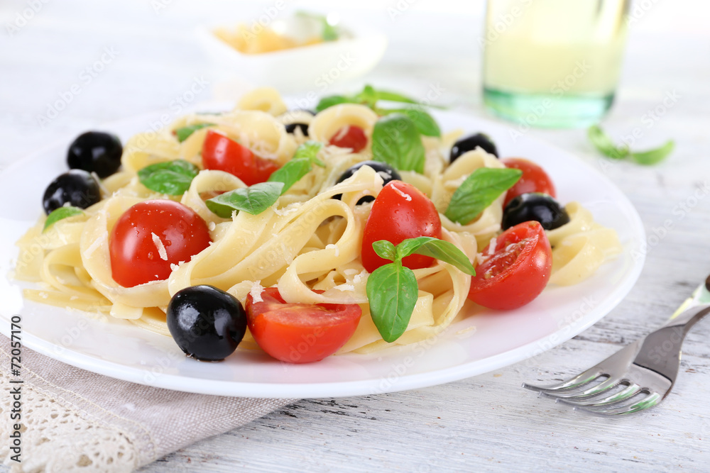 Spaghetti with tomatoes, olives and basil leaves