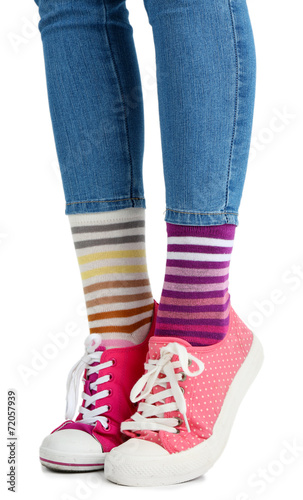 Female legs in colorful socks and sneakers isolated on white