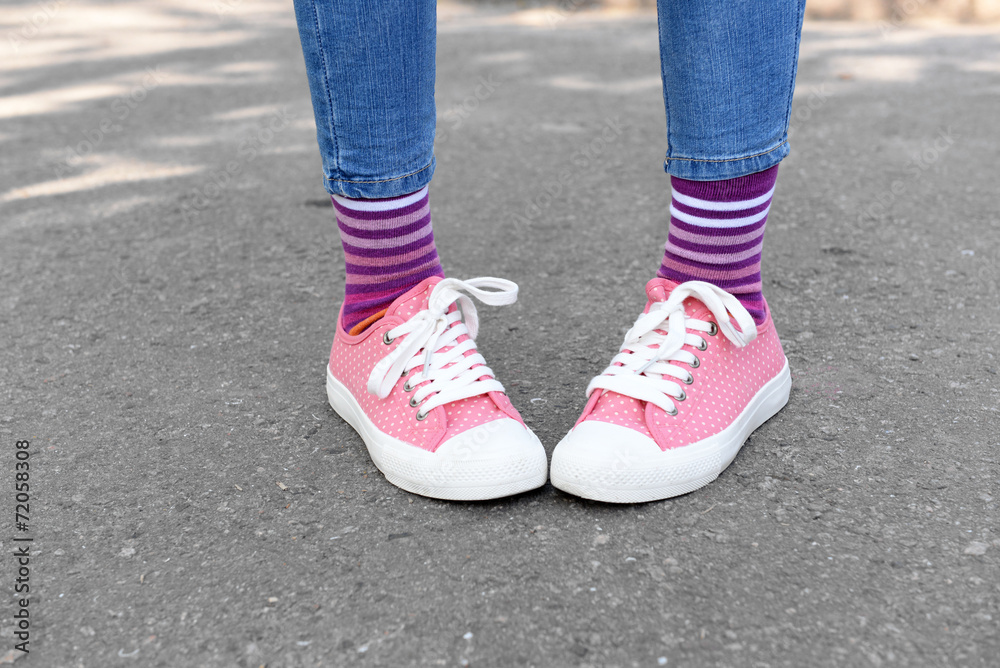 Female legs in colorful socks and sneakers outdoors