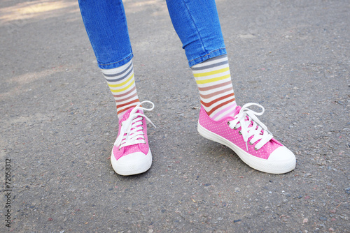 Female legs in colorful socks and sneakers outdoors