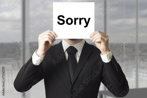 businessman hiding face behind sign sorry photo