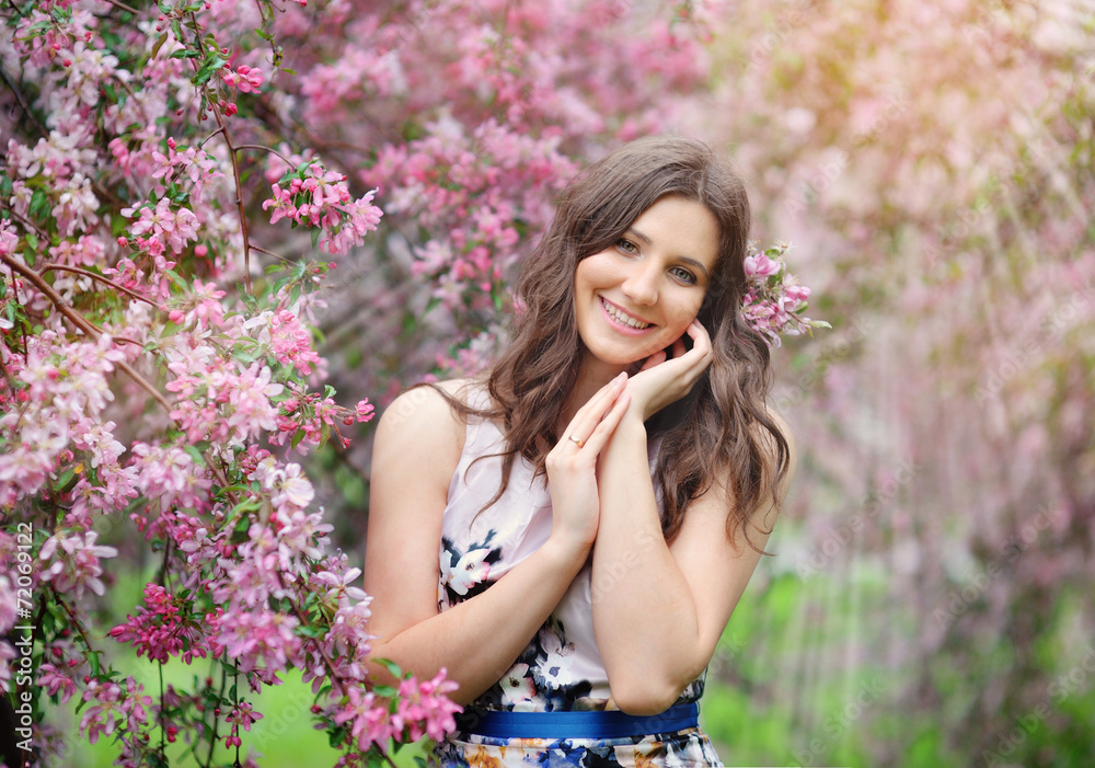 Beautiful girl in spring garden among blooming trees with pink Beautiful girl in spring garden among blooming trees with pink