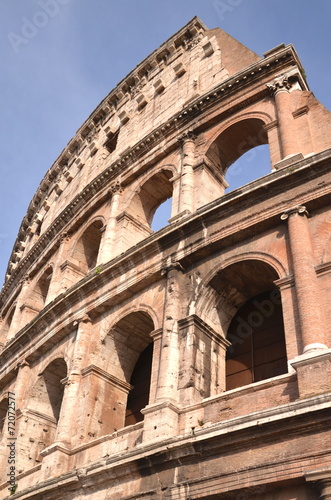 Monumentalne coloseum w Rzymie na tle niebieskiego nieba, Włochy #72072577
