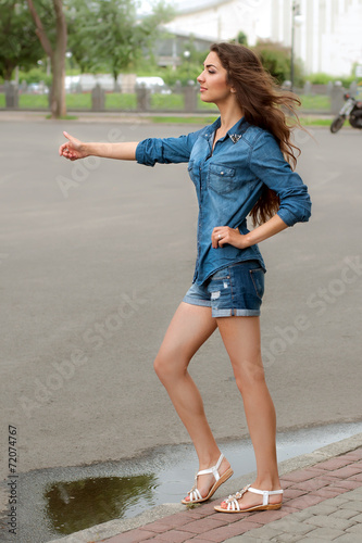 Fotografie Side view of a woman hitchhiking on city road
