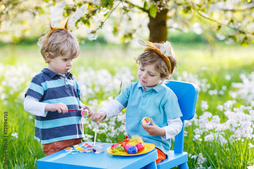Two little boy friends in Easter bunny ears coloring eggs Two little boy friends in Easter bunny ears coloring eggs