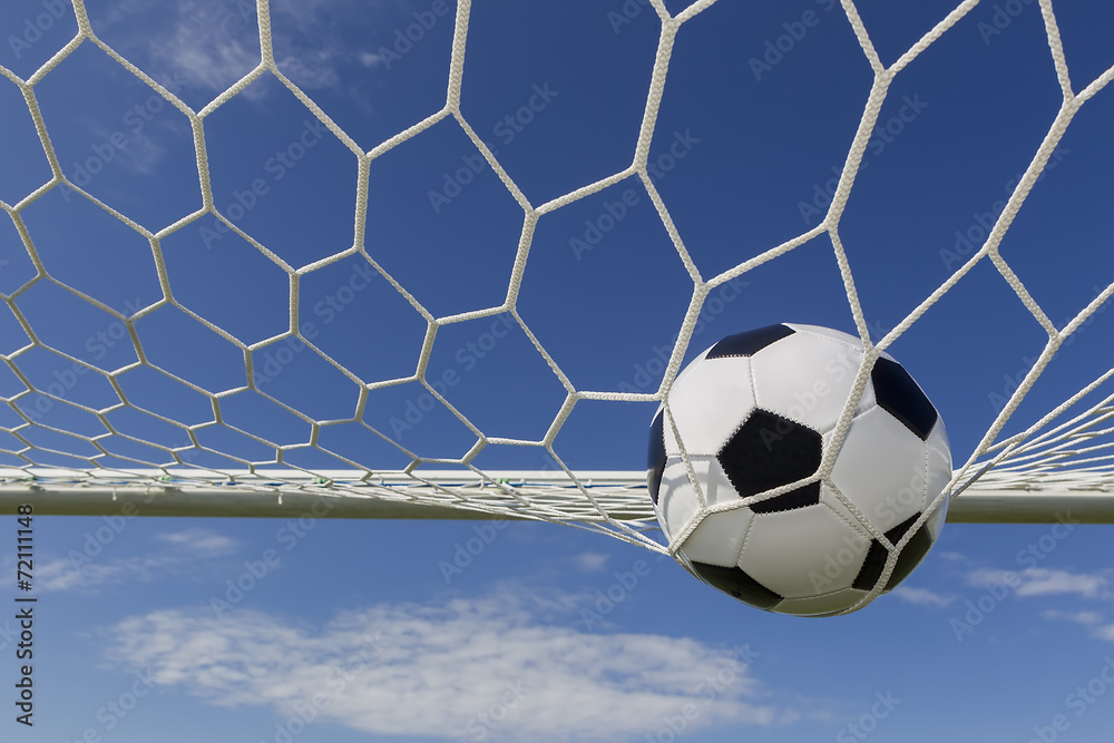 Naklejka premium Soccer football in Goal net with sky field.