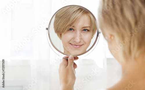 Beautiful healthy young woman looking in the mirror