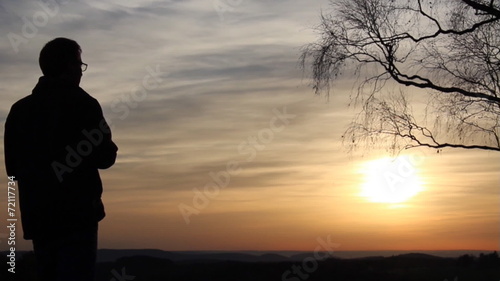 Mann mit Fernglas beim Sonnenuntergang