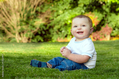 Smiling happy baby playing on the grass outdoors