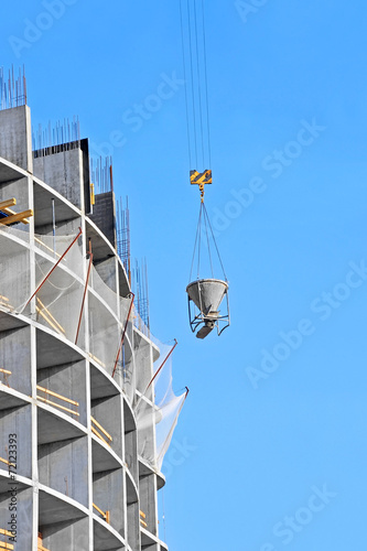 Crane lifting concrete mixer container against blue sky © Unkas Photo