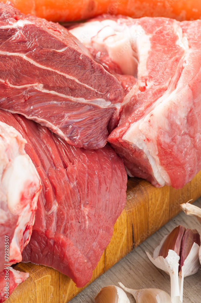 Tagli di carne bovina e suina cruda appoggiati sul tagliere